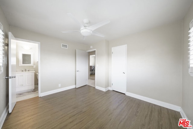 unfurnished bedroom featuring sink, ensuite bathroom, ceiling fan, and dark hardwood / wood-style flooring