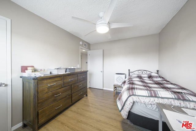 bedroom with ceiling fan, light hardwood / wood-style floors, and a textured ceiling