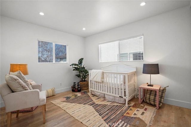 bedroom with hardwood / wood-style flooring and a nursery area