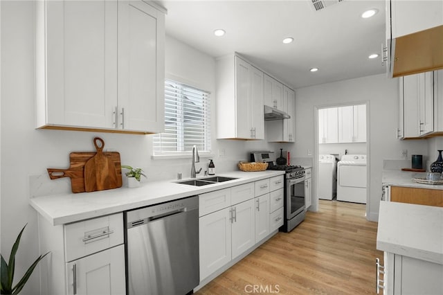 kitchen featuring washing machine and dryer, sink, light hardwood / wood-style flooring, appliances with stainless steel finishes, and white cabinets