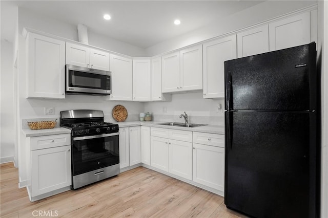 kitchen featuring sink, white cabinets, appliances with stainless steel finishes, and light wood-type flooring