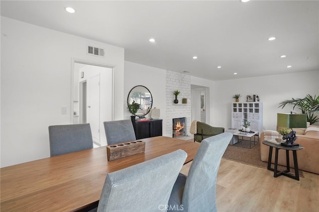 dining space featuring a brick fireplace and light wood-type flooring