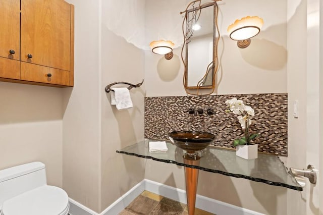 bathroom featuring backsplash, sink, and toilet