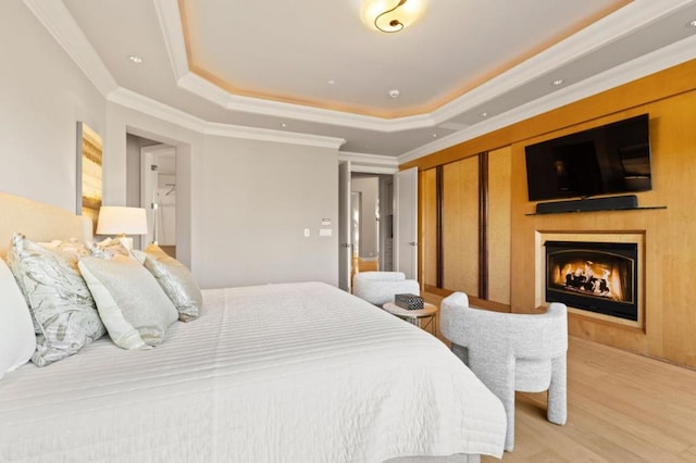 bedroom featuring a closet, ornamental molding, light hardwood / wood-style flooring, and a tray ceiling