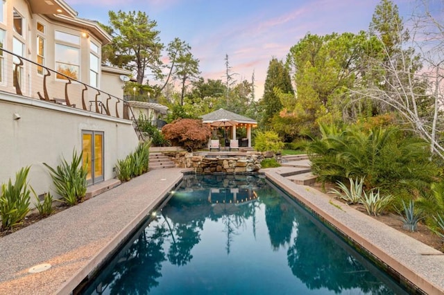 pool at dusk featuring a gazebo