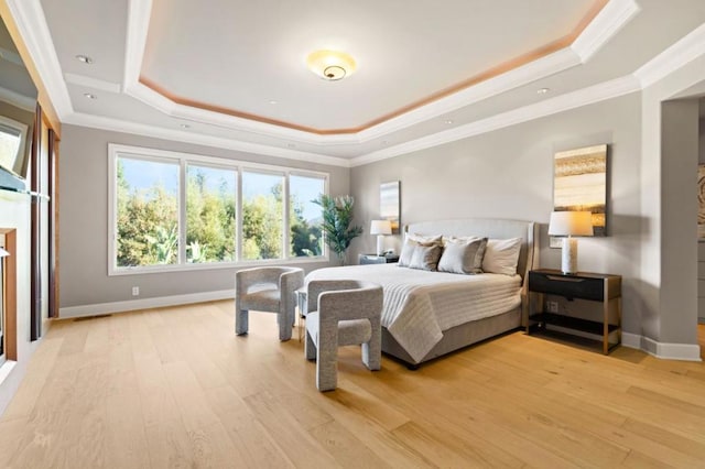 bedroom featuring ornamental molding, a raised ceiling, and light wood-type flooring