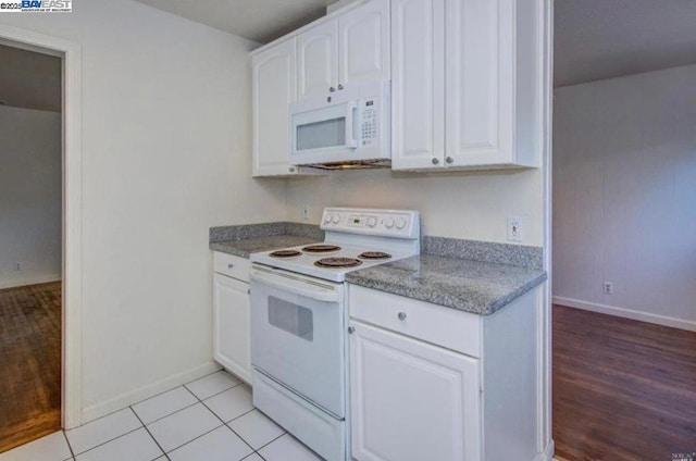 kitchen featuring white appliances, white cabinets, and light tile patterned flooring