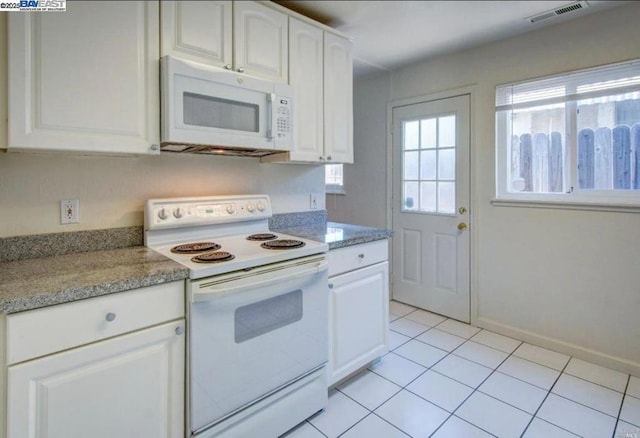 kitchen with light tile patterned floors, white cabinets, light stone counters, and white appliances