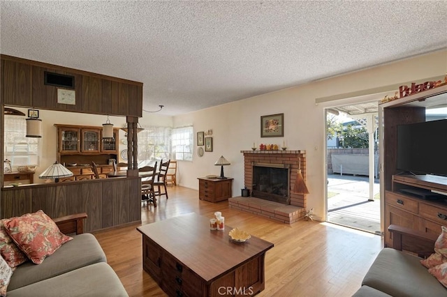 living room with a textured ceiling, a fireplace, and light hardwood / wood-style flooring