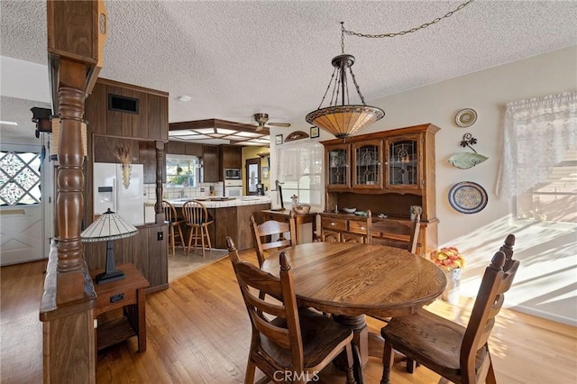 dining space with a textured ceiling and light hardwood / wood-style flooring