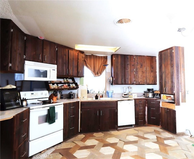 kitchen featuring dark brown cabinetry, sink, and white appliances