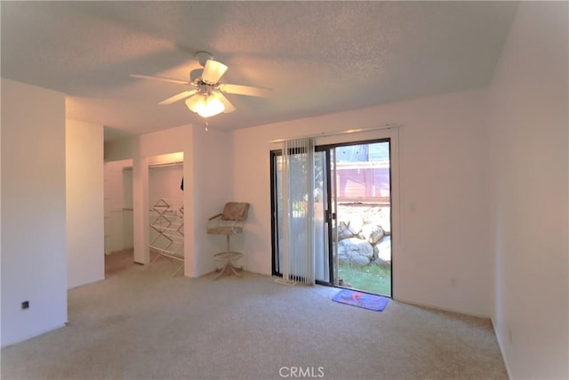 carpeted empty room with ceiling fan and a textured ceiling