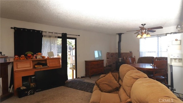 interior space with ceiling fan, a wood stove, light colored carpet, and a textured ceiling