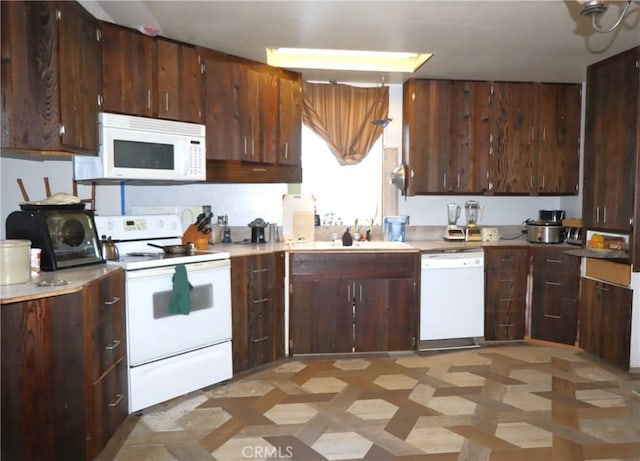 kitchen with dark brown cabinetry, sink, and white appliances