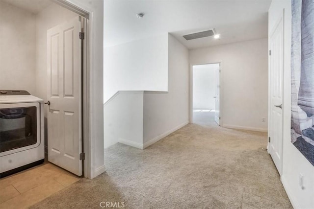 clothes washing area featuring light carpet and washer / dryer