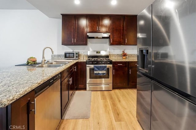 kitchen featuring light stone countertops, stainless steel appliances, light hardwood / wood-style floors, and sink