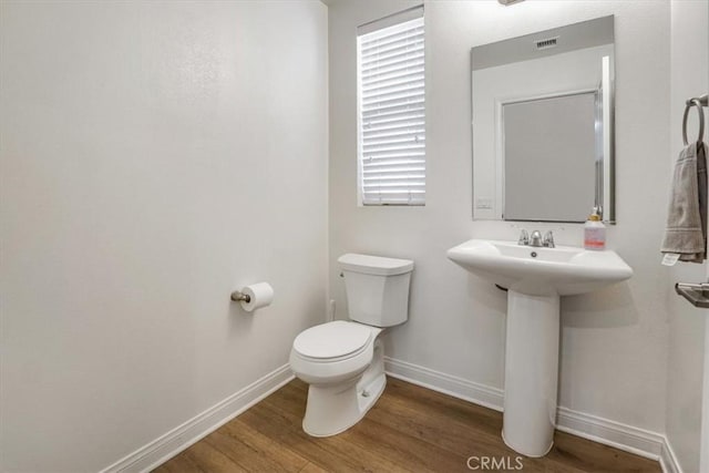 bathroom featuring toilet, sink, and hardwood / wood-style floors