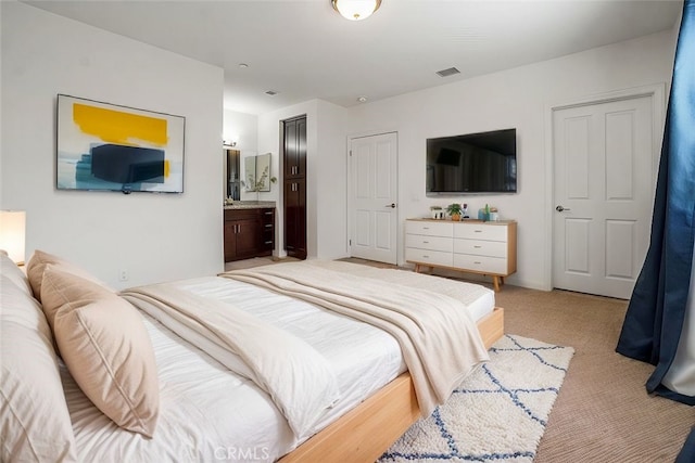 bedroom featuring ensuite bath and light carpet