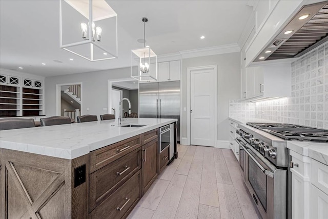 kitchen with pendant lighting, an island with sink, white cabinets, custom exhaust hood, and high end appliances