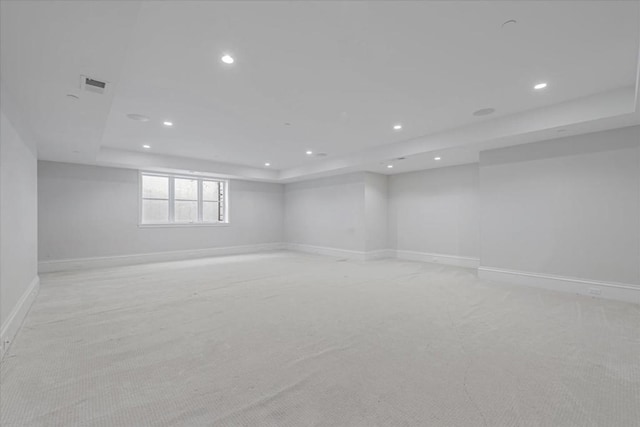 carpeted spare room featuring a tray ceiling