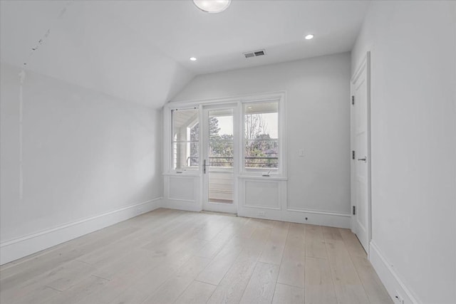 unfurnished room with lofted ceiling and light wood-type flooring