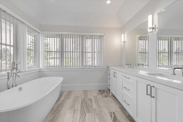 bathroom featuring lofted ceiling, vanity, and a washtub