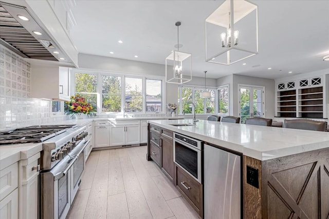 kitchen with sink, decorative light fixtures, appliances with stainless steel finishes, custom range hood, and white cabinets