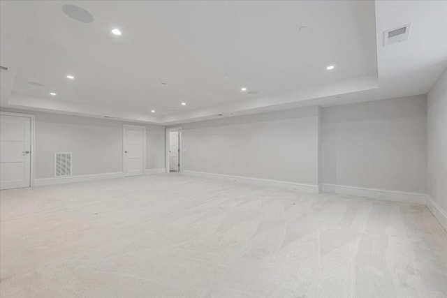 carpeted empty room featuring a tray ceiling