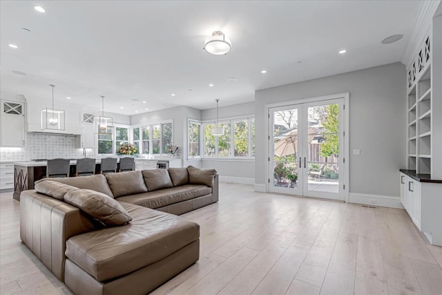 living room with sink, light wood-type flooring, and french doors