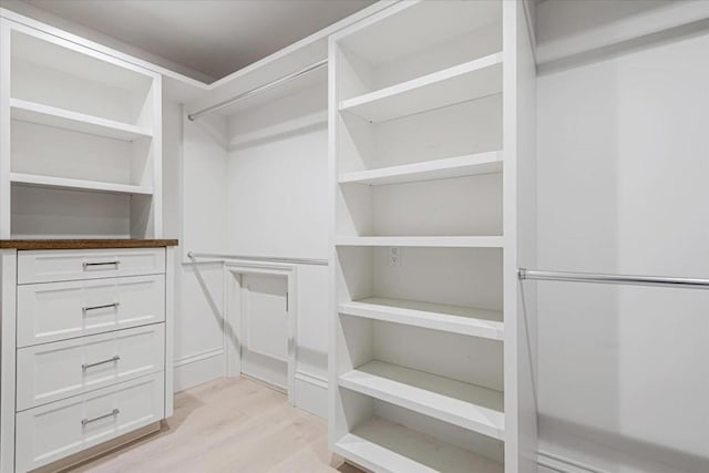 walk in closet with light hardwood / wood-style flooring