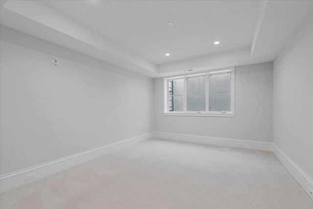 carpeted empty room featuring a tray ceiling