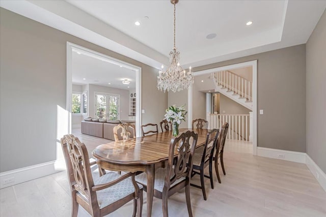 dining area featuring light hardwood / wood-style flooring, a chandelier, and a tray ceiling