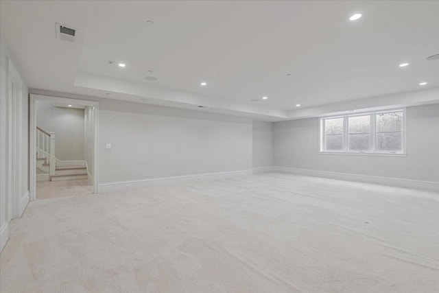 empty room with a raised ceiling and light carpet