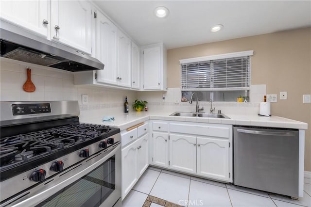 405 W Mountain View Ave Unit 11, La Habra, CA 90631 - kitchen featuring white cabinets, under cabinet range hood, a sink, stainless steel appliances, and decorative backsplash