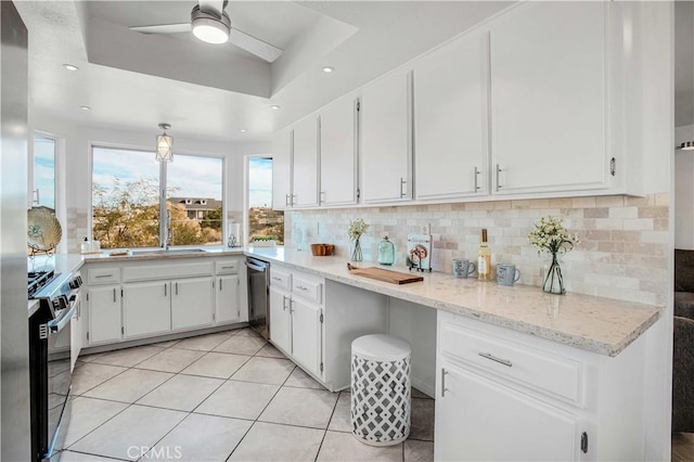 kitchen featuring decorative backsplash, white cabinets, a raised ceiling, and stainless steel appliances