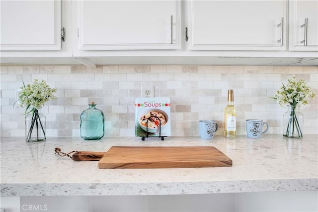 details featuring white cabinetry, decorative backsplash, and light stone countertops