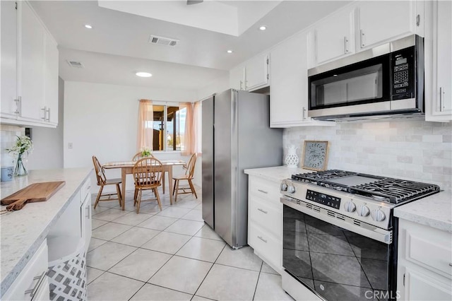 kitchen featuring light tile patterned floors, light stone countertops, white cabinets, and stainless steel appliances