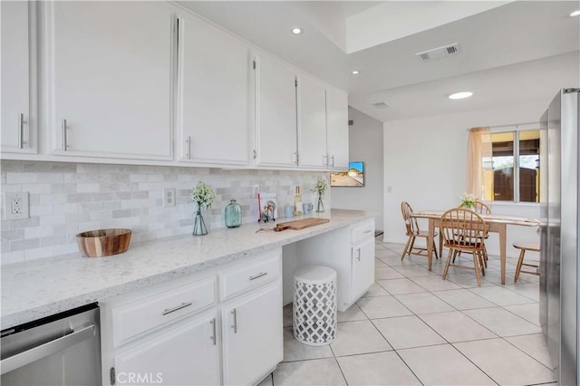 kitchen featuring white cabinets, appliances with stainless steel finishes, tasteful backsplash, light tile patterned flooring, and light stone counters