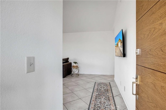 hallway with light tile patterned floors and lofted ceiling