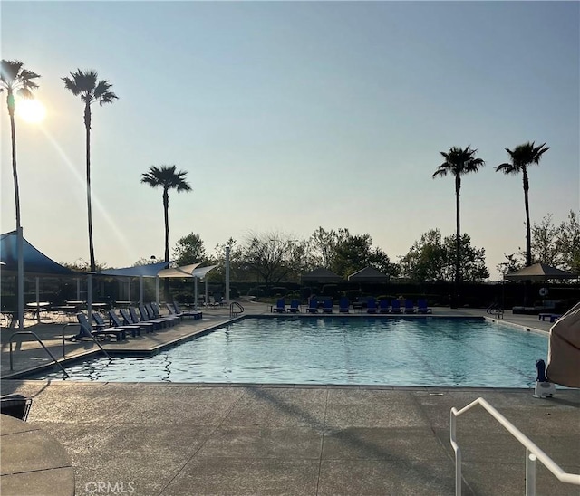 pool at dusk featuring a patio