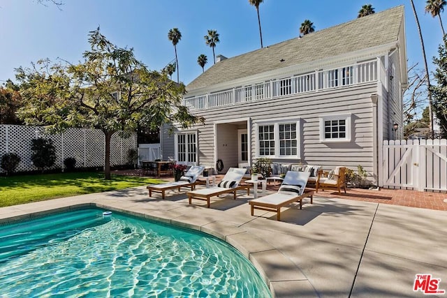 back of property featuring an outdoor hangout area, a fenced in pool, and a patio area