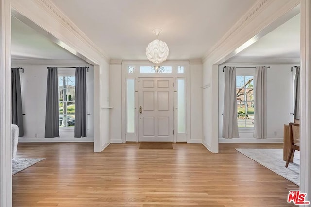 entryway featuring light wood-type flooring, plenty of natural light, and crown molding