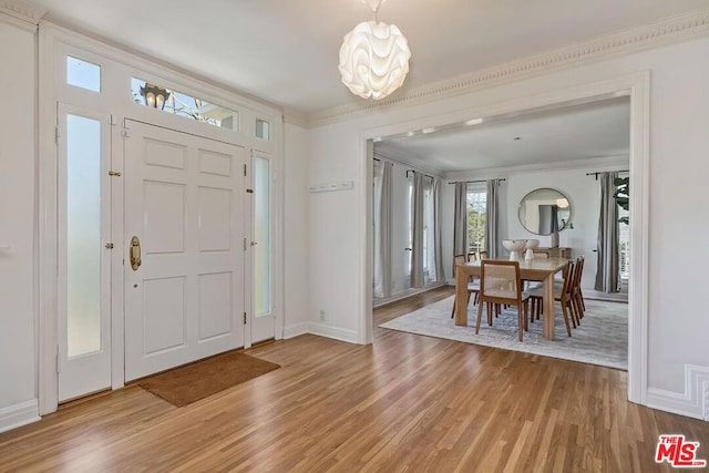 entryway with ornamental molding, hardwood / wood-style floors, and a notable chandelier