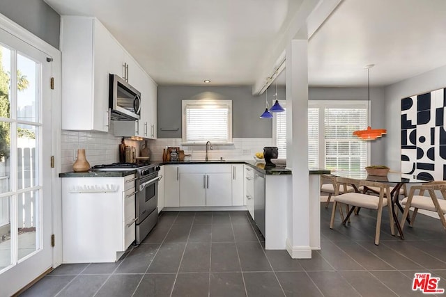 kitchen with pendant lighting, white cabinets, dark tile patterned floors, stainless steel appliances, and sink