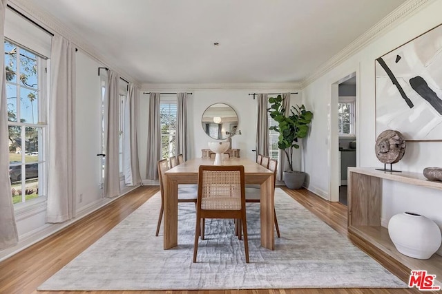 dining space with light wood-type flooring and ornamental molding