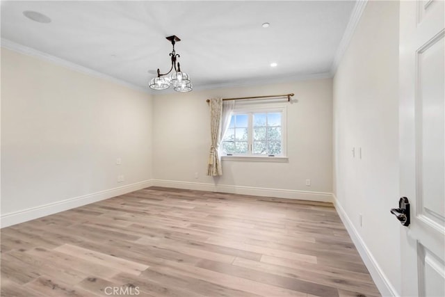 spare room with light wood-type flooring, ornamental molding, and a notable chandelier