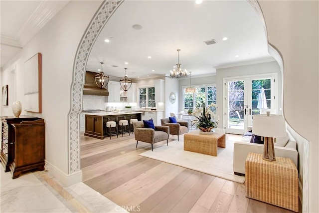 living room featuring light wood-type flooring, french doors, and crown molding