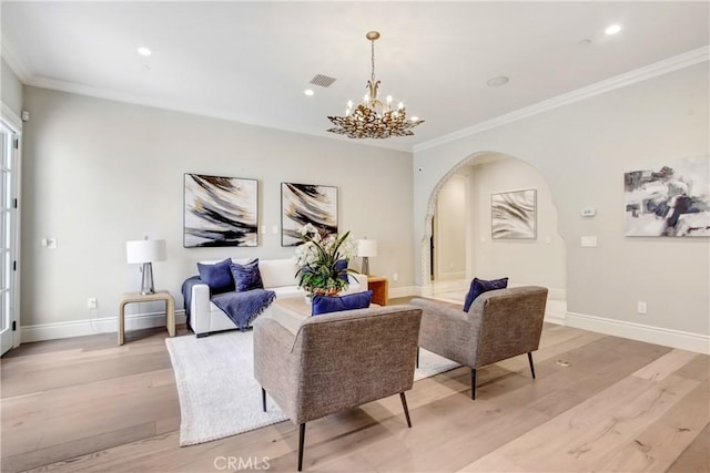 living room with light wood-type flooring, an inviting chandelier, and crown molding