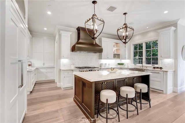 kitchen featuring premium range hood, a kitchen breakfast bar, white cabinets, and a center island