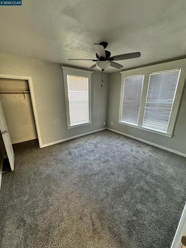 unfurnished bedroom featuring dark colored carpet, ceiling fan, a textured ceiling, and a closet